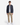 A person stands facing forward against a plain white background, wearing the PROJEK RAW CORDUROY RELAXED FIT SHIRT in a dark shade over a white T-shirt, paired with khaki pants and white sneakers for all-day comfort.