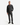 A man stands facing forward against a plain white background, wearing the PROJEK RAW RELAXED FIT DENIM SHIRT in dark gray with matching gray pants and black boots, his left hand in his pocket for all-day comfort.