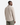 A man is standing and facing away, wearing the PROJEK RAW JACQUARD KNIT OVERSHIRT in light beige with a subtle herringbone pattern, paired with olive green pants against a plain white background.