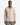 A man wearing the PROJEK RAW JACQUARD KNIT OVERSHIRT, a beige relaxed shirt-jacket with chest pockets and a subtle herringbone pattern, stands against a plain white background.