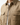 A person is wearing the PROJEK RAW KNIT CAVALRY TWILL OVERSHIRT in beige, featuring flap chest pockets, layered over a white textured shirt. The image displays the upper torso without showing the person’s face.