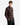 A man is seen standing slightly turned to the side, gazing off to the left against a plain white background. He wears black pants and the FLANNEL PLAID OVERSHIRT from PROJEK RAW, featuring a brown plaid pattern and front pockets. The timeless design and sturdy fabric make this overshirt a versatile option that pairs effortlessly with everything from jeans to cavalry twill trousers.