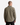 A person with short hair stands facing away against a plain white background, wearing the PROJEK RAW TWILL OVERSHIRT in olive green paired with black pants. This lightweight overshirt, ideal for transitional weather, features a small rectangular patch near the top.