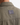 Close-up of the back of the TWILL OVERSHIRT by PROJEK RAW in khaki, featuring a rectangular black label sewn near the collar. The lightweight design makes this jacket ideal for transitional weather, and it is shown being worn.