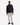 A man stands facing forward against a plain white background wearing the PROJEK RAW BUNGEE SOLID OVERSHIRT in navy, featuring a snap-button front and chest pockets, paired with beige pants and black sneakers.