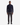 A man stands facing forward against a plain white background, wearing the PROJEK RAW SHAKER RIB MOCK NECK 1/4″ ZIP SWEATER in navy, which features a subtle textured shaker knit. He pairs it with dark gray pants and black shoes.