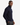A man stands sideways, looking at the camera. He wears a PROJEK RAW SHAKER RIB MOCK NECK 1/4″ ZIP SWEATER in navy blue and dark pants, with one hand in his pocket. The background is plain white.