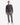 A man stands against a plain white background wearing the PROJEK RAW SHAKER RIB CREWNECK SWEATER in dark gray, paired with light gray pants and white sneakers.