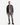 A man stands against a white background wearing a PROJEK RAW gray jacket, white t-shirt, BARU CLASSIC STRAIGHT FIT DENIM jeans by PROJEK RAW in a grey wash, and black shoes. He has a neutral expression and short hair.