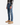 A person is shown from the shoulders down, wearing a plaid shirt, tan suede boots, and PROJEK RAW’s BARU CLASSIC STRAIGHT FIT DENIM in a stone blue wash, standing against a white background.