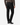 A person shown from the back, standing against a plain white background, is wearing PROJEK RAW’s BARU CLASSIC COLORED KNIT DENIM in black, paired with a brown ribbed sweater and black dress shoes.