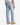 A person is shown from the back, standing against a plain white background, wearing PROJEK RAW’s DREW BAGGY FIT DENIM jeans, a white sleeveless shirt, and tan boots.