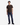 A person wearing a dark brown T-shirt, PROJEK RAW ATLAS ATHLETIC FIT DENIM in a midnight blue wash with a tapered leg, and black shoes stands against a plain white background, looking straight ahead with a neutral expression.
