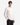 A young man models the PROJEK RAW LUX ESSENTIAL JERSEY LONG SLEEVE T-SHIRT in plain white—an essential wardrobe staple—paired with dark plaid pants. He stands against a light gray background with one hand in his pocket, gazing slightly to the side.