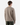 A man with light brown hair is standing with his back to the camera, wearing the PROJEK RAW RELAXED FIT KNIT CORD CREWNECK SWEATER in taupe and dark green pants against a plain white background.