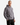 A person wearing the PROJEK RAW RELAXED FIT TERRY FLEECE HOODIE in gray and black pants stands with one hand in their pocket, facing slightly to the side against a plain white background.
