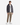 A person stands facing forward against a plain white background, wearing the PROJEK RAW RELAXED FIT BONDED ZIP-UP HOODIE in dark color over a white t-shirt, paired with tan pants and white sneakers.