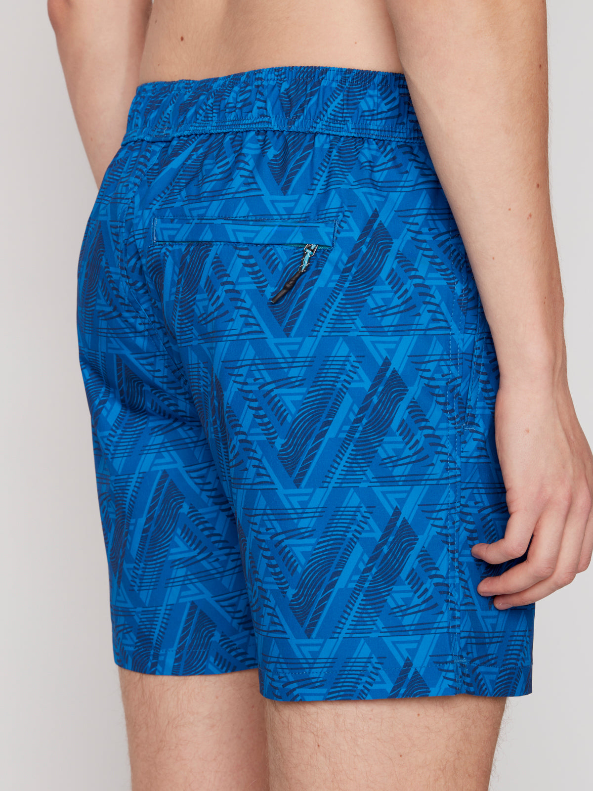 A person models Projek Raw BRYSON-BLUE swim trunks with a blue pattern and zippered back pocket, shown from waist to mid-thigh against a plain light background.