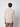 A man with short, curly brown hair faces away from the camera, wearing the PROJEK RAW Mens Half-zip Cashmere Touch Sweater in light beige and brown pants against a plain, light background.