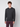 A young man with curly hair wears a PROJEK RAW Mens Long Sleeve Hoodie with Kangaroo Pocket in dark gray and maroon pants, standing against a plain light gray background, facing forward with a neutral expression.