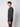 A young man with curly brown hair models the PROJEK RAW Mens Long Sleeve Hoodie with Kangaroo Pocket in dark gray and maroon pants, standing sideways and looking at the camera against a plain light gray background.