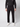 A person is seen from the shoulders down, standing against a plain light background, wearing PROJEK RAW Mens Bungee Relaxed Chino Pant, a black long-sleeve shirt, and white sneakers.