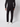 A person models the back view of PROJEK RAW Mens Bungee Relaxed Chino Pant in black, paired with a black long-sleeve shirt and white sneakers, standing against a plain light background.