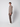 A young man stands sideways against a plain light background, wearing a taupe button-up shirt, PROJEK RAW Mens Bungee Relaxed Chino Pant, and white sneakers. He looks forward with a neutral expression.