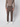 A person wearing a taupe button-up shirt, PROJEK RAW Mens Bungee Relaxed Chino Pant in brown, and white sneakers stands facing forward against a plain light background. The image is cropped above the shoulders.