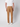 A person stands facing away from the camera, wearing PROJEK RAW Mens Bungee Relaxed Chino Pant in tan with a white short-sleeve shirt and white sneakers, set against a plain light background.