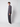 A young man stands sideways against a plain white background, wearing a grey button-up shirt, PROJEK RAW Mens Bungee Loose Cargo Pant, and white sneakers. He faces forward with a neutral expression and relaxed posture.