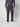 A person models the PROJEK RAW Mens Bungee Loose Cargo Pant in dark gray with a matching shirt and white sneakers, standing against a plain light backdrop. Their head is not shown in the image.