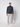 A man stands facing forward against a plain light background, wearing a dark blue turtleneck sweater, PROJEK RAW Mens Relaxed 5-Pocket Pant in light gray, and white sneakers.