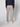 A person faces away from the camera, wearing light gray PROJEK RAW Mens Relaxed 5-Pocket Pant, a dark long-sleeve top, and white sneakers against a plain light background.