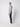 A young man stands in profile against a plain light background, wearing a gray hoodie, white sneakers, and PROJEK RAW Men’s 5-Pocket Pant made from stretch fabric.
