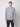 A young man with short light brown hair and a neutral expression wears the PROJEK RAW Mens Long Sleeve Hoodie with Kangaroo Pocket in light gray and dark pants, standing against a plain light background, facing forward.