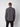 A man with short brown hair wears the PROJEK RAW Mens Casual Dress Shirt with Logo Detail and black pants, standing facing away from the camera against a plain light grey background.