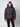 A young man wears the PROJEK RAW Mens Quilted Ecofill Puffer with hood, featuring button and zipper closure plus front pockets, while standing against a plain light background.