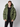 A young man with short light brown hair wears the PROJEK RAW Mens Quilted Ecofill Puffer with hood in green over a black sweater and black pants, standing against a plain light gray background.