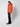 A man in a bright orange PROJEK RAW Mens Quilted Ecofill Puffer with hood, black pants, boots, and a black beanie stands against a plain white background, looking slightly to the side.