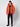A person stands against a plain background wearing a PROJEK RAW Mens Quilted Ecofill Puffer with hood in bright orange, paired with black pants, boots, and beanie. Their pose is relaxed, arms at their sides.