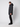 A person stands sideways against a plain light background, wearing the PROJEK RAW Mens Textured Ripstop Ecofill Quilted Parka with Hood in black, paired with black pants and boots.