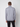 A man faces away from the camera, wearing the PROJEK RAW Mens Half-zip Cashmere Touch Sweater in light grey with black pants, set against a plain light grey background.