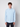A young man with curly brown hair wears the PROJEK RAW Mens 24/7 Button-up Shirt in light blue and dark pants, standing against a plain light background, facing the camera with a neutral expression.