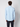 A man with short, curly brown hair is shown from behind wearing the PROJEK RAW Mens 24/7 Button-up Shirt in light blue and dark pants—an ideal travel-friendly choice—standing against a plain white background.
