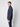 A young man stands sideways facing left, wearing the PROJEK RAW Mens 24/7 Button-up Shirt in navy blue with dark jeans against a plain light gray background.