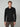A man with short blond hair wears the PROJEK RAW MENS 24/7 BUTTON-UP KNIT SHIRT in black with brown pants, standing against a plain light gray background.