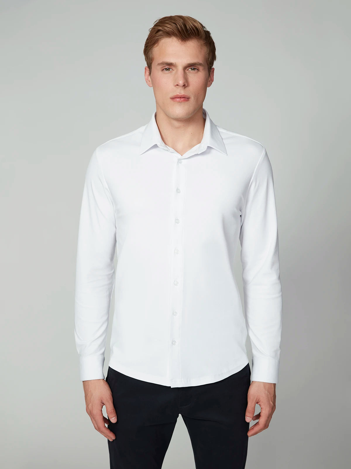 A man with short blond hair wears the PROJEK RAW MENS 24/7 BUTTON-UP KNIT SHIRT and black pants, facing the camera against a plain light gray background.