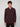 A young man with curly brown hair wears the PROJEK RAW MENS LONG SLEEVE 4WAY STRETCH TWILL SHIRT in dark maroon and black pants, standing against a plain, light gray background.