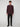 A young man with curly brown hair stands facing forward, wearing the PROJEK RAW MENS LONG SLEEVE 4WAY STRETCH TWILL SHIRT in dark maroon, paired with black pants and shoes, against a plain light gray background.
